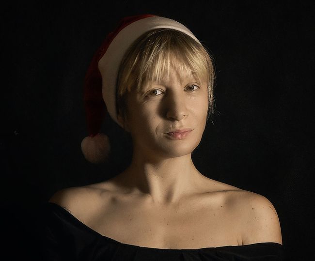 Portrait of young woman against black background