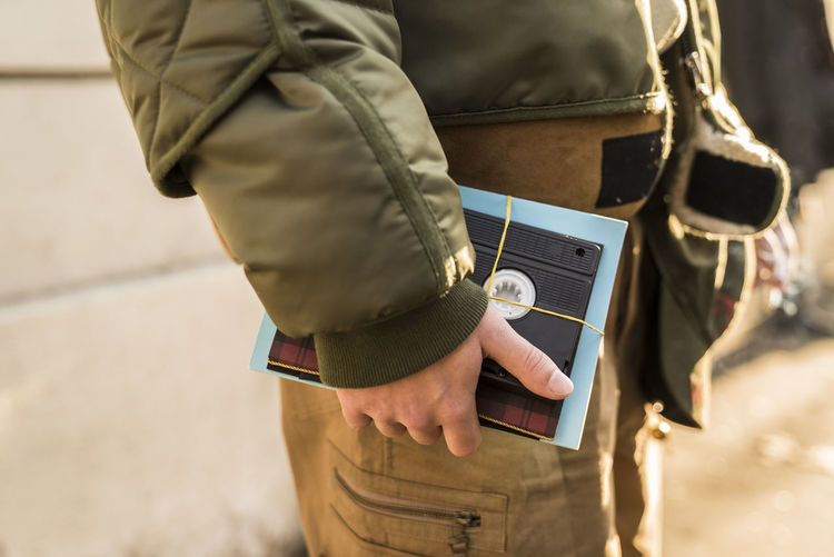 Midsection of man holding book and audio cassette