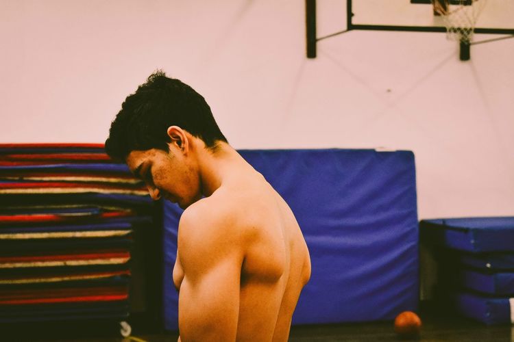 Side view of shirtless boy against wall