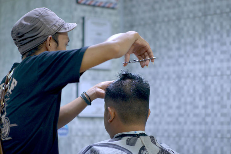 Barber cutting man hair in salon