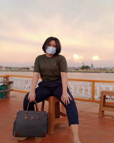 Full length of woman sitting against sky during sunset
