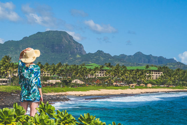 Rear view of boy looking at sea against mountains