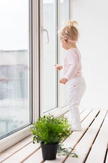 Side view of girl standing near window