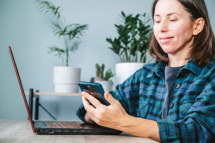 A happy smiling woman looking at her mobile while working from home