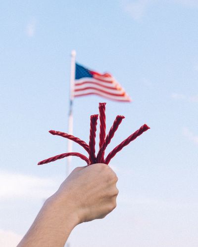 Cropped hand holding string against american flag