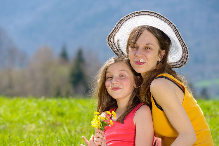 Portrait of happy mother and daughter on grassy field at park