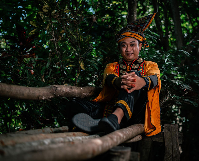 Portrait of boy sitting on wood in forest,tradisonal bajau samah