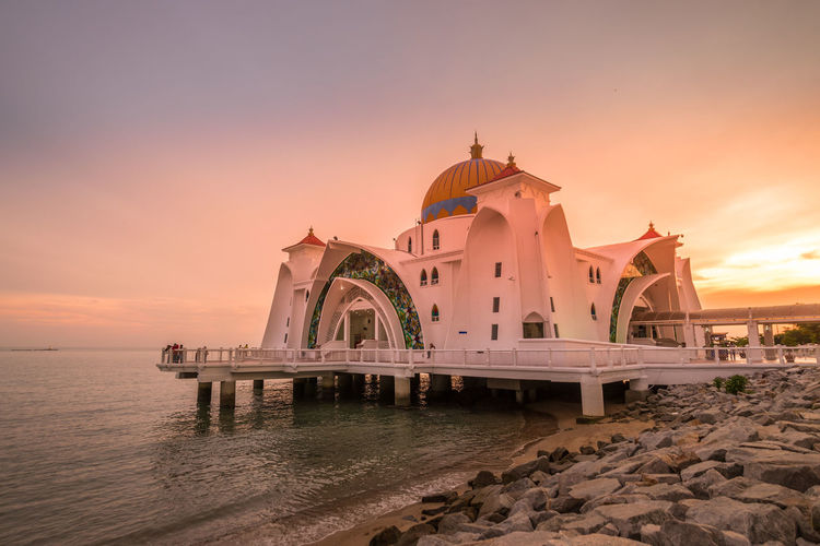Melaka straits mosque by sea against sky during sunset