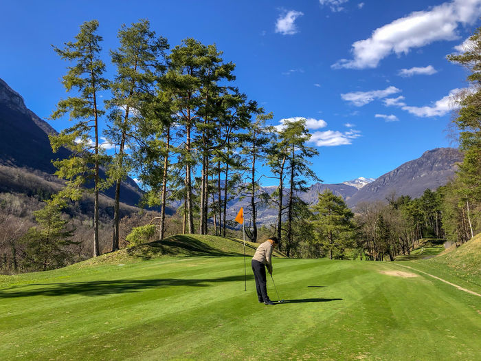 Golfer on putting green with mountain view in italy.