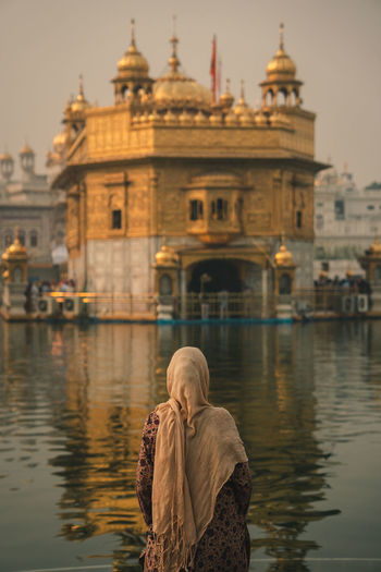 Rear view of woman on the river against the golden temple