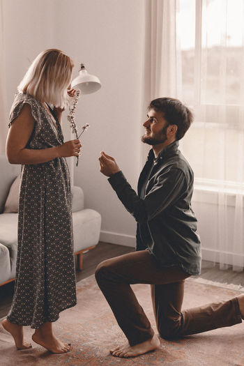 Smiling man proposing girlfriend at home