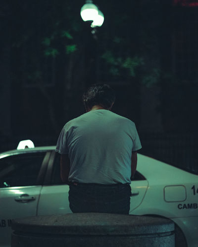 Rear view of man standing on street at night