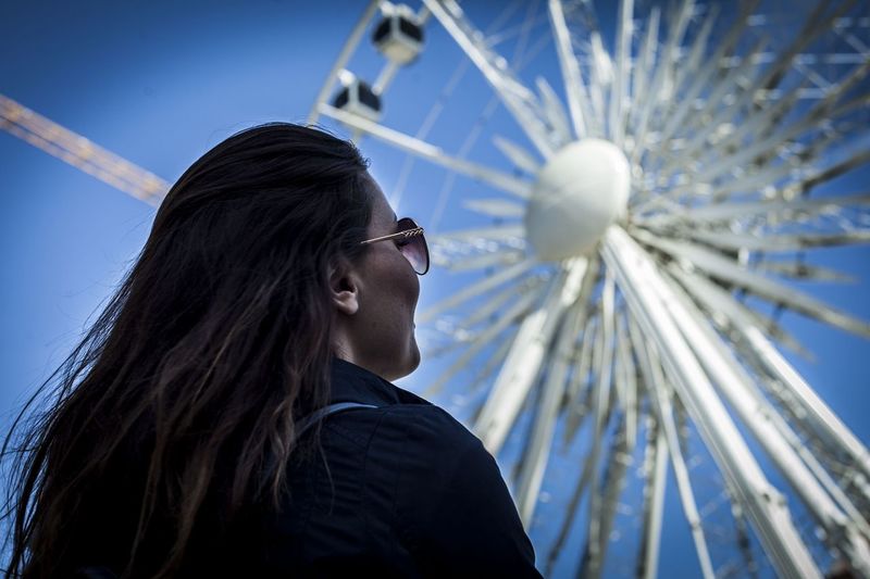 Low angle view of young woman looking at ferris wheel
