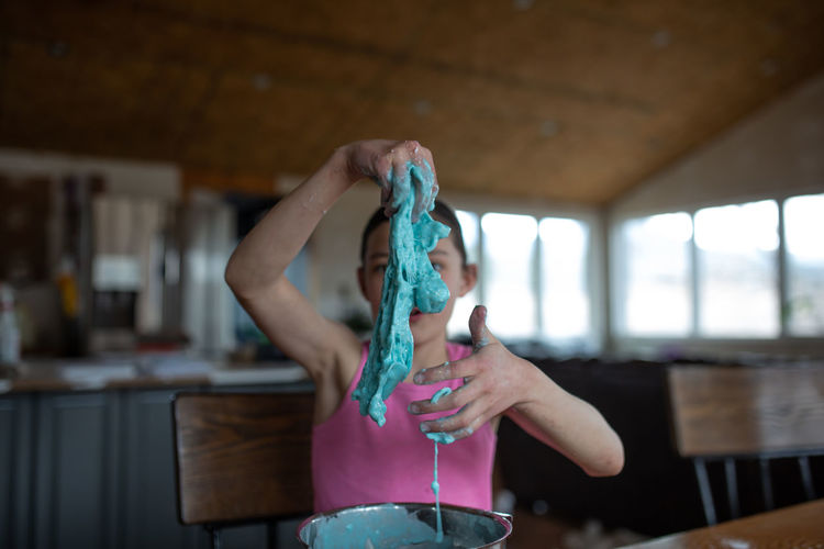 Girl stretching blue slime in her hands