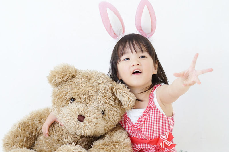 Portrait of cute girl with stuffed toy against white background
