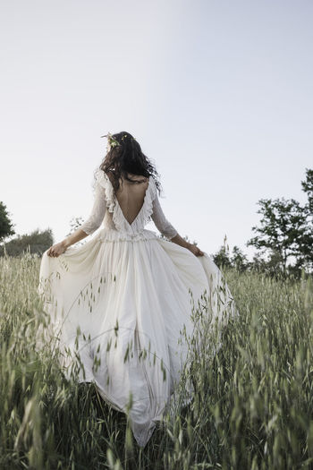 Bride walking in the countryside in a long wedding dress.
