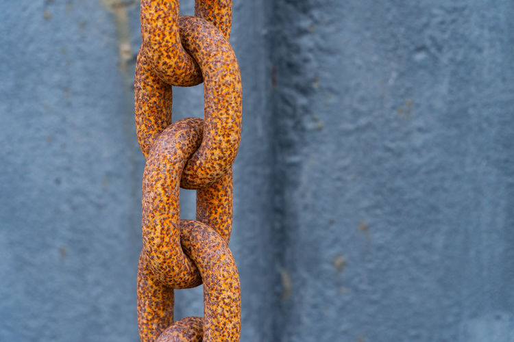 Close-up of rusty chain hanging against wall