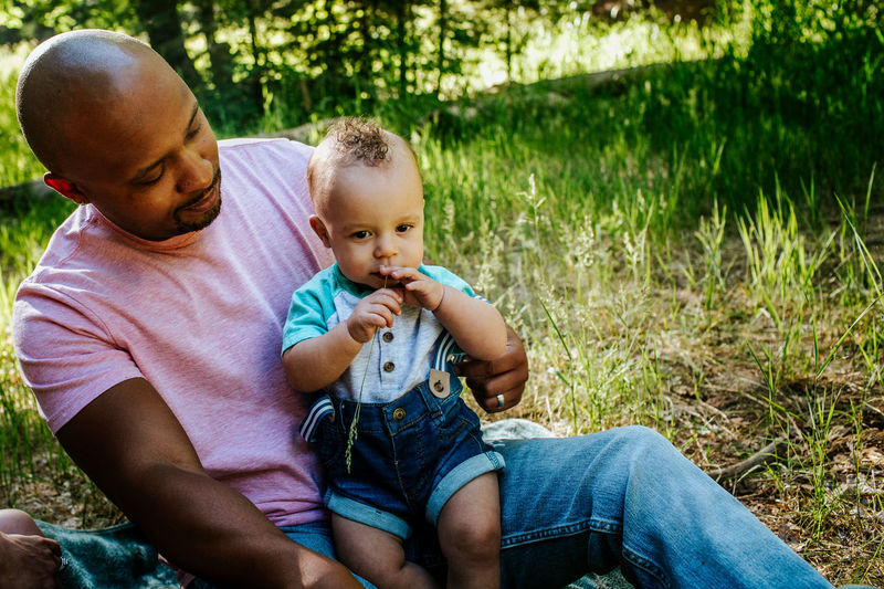 Father looking at infant son outside in nature