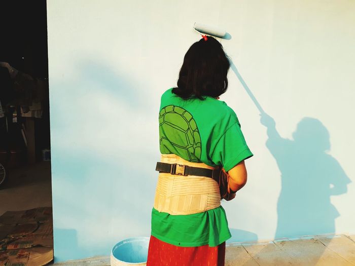 Rear view of woman painting wall