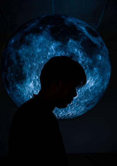Silhouette young man against moon at night