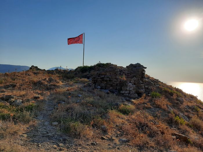 Low angle view of flag on rock against sky