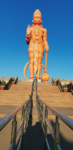 Low angle view of 108 feet tall statue of lord hanuman on  building against clear blue sky