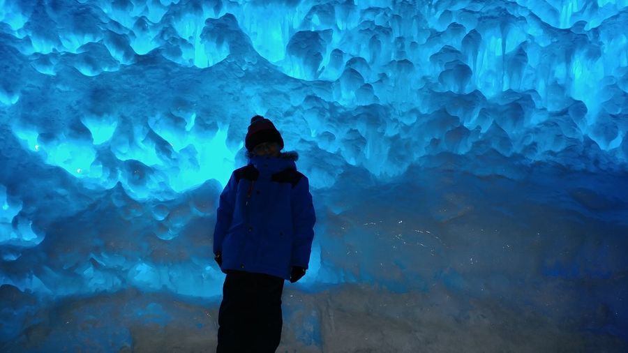 Boy wearing warm clothing standing in ice cave