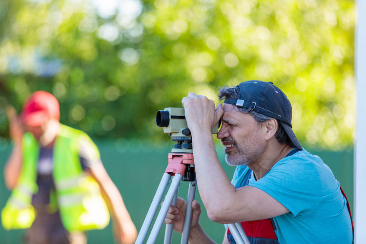 A man works with an optical level to level the landscape.