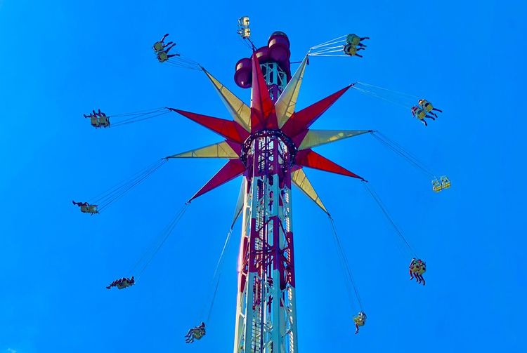 Low angle view of chain swing ride against clear blue sky