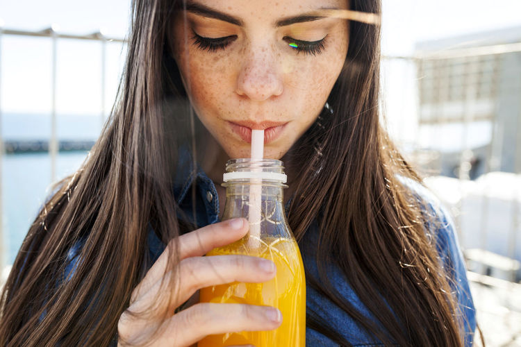 Close-up portrait of young woman drinking drink