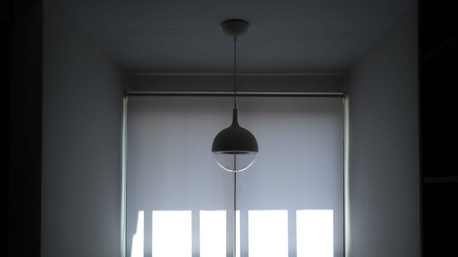 Low angle view of illuminated pendant light hanging in building