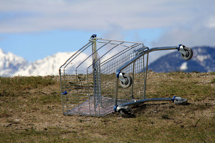 Close-up of shopping cart on field against sky