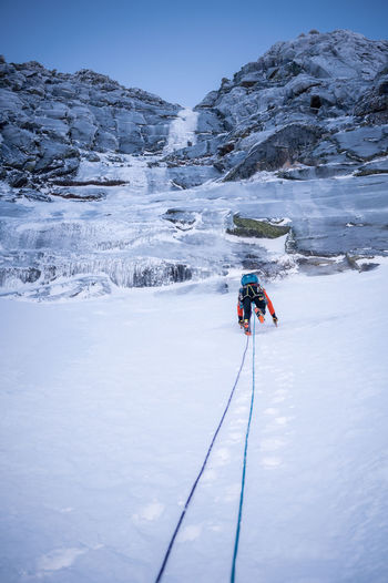 A climber ascends a steep snow section before an ice climb
