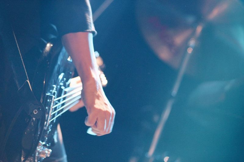 Midsection of guitarist playing bass guitar on stage