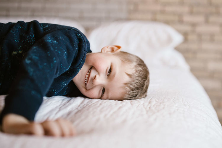 Portrait of smiling boy on bed at home