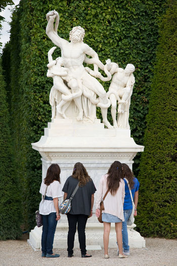 Rear view of friends looking at greek god statues