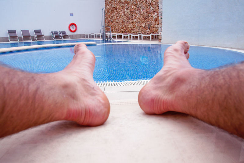 Low section of person relaxing in swimming pool