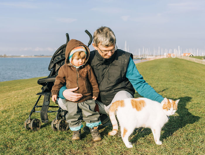 Mature man with granddaughter and cat on field