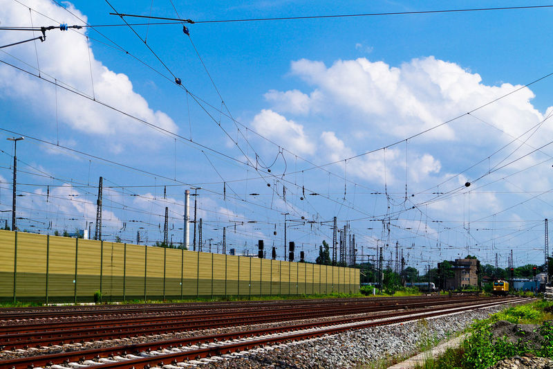 Electricity cables over tracks against sky