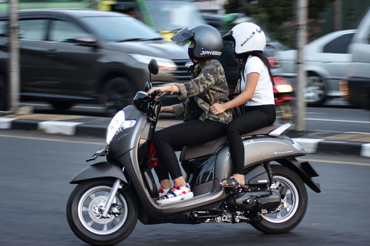 Man riding motor scooter on road