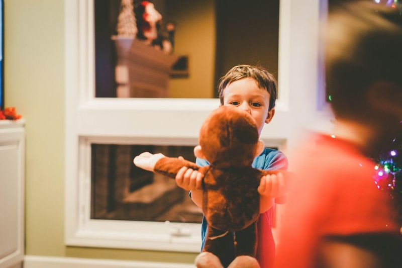 Boy holding monkey toy at home