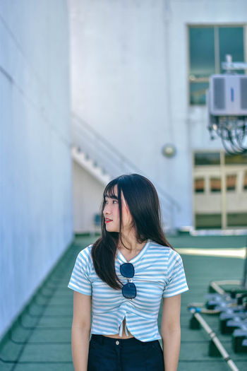 Young woman standing on floor against building