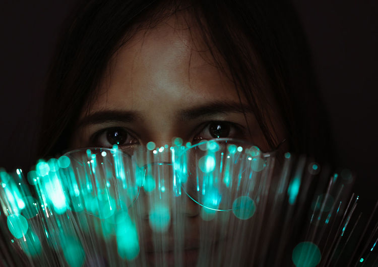 Close-up portrait of young woman by fiber optic