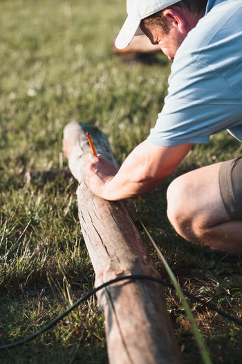 Man measuring wood with tape measure at field 
