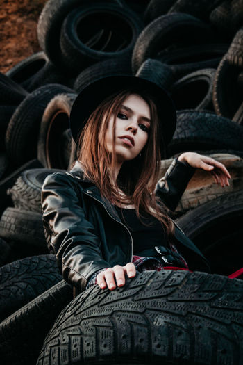 Portrait of young woman sitting on tires