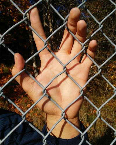 Close-up of woman hand holding chainlink fence
