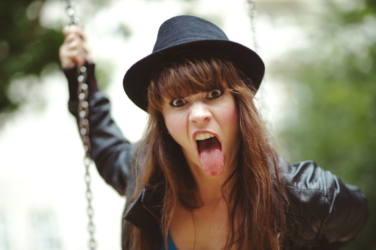 Portrait of angry woman sticking out tongue at playground