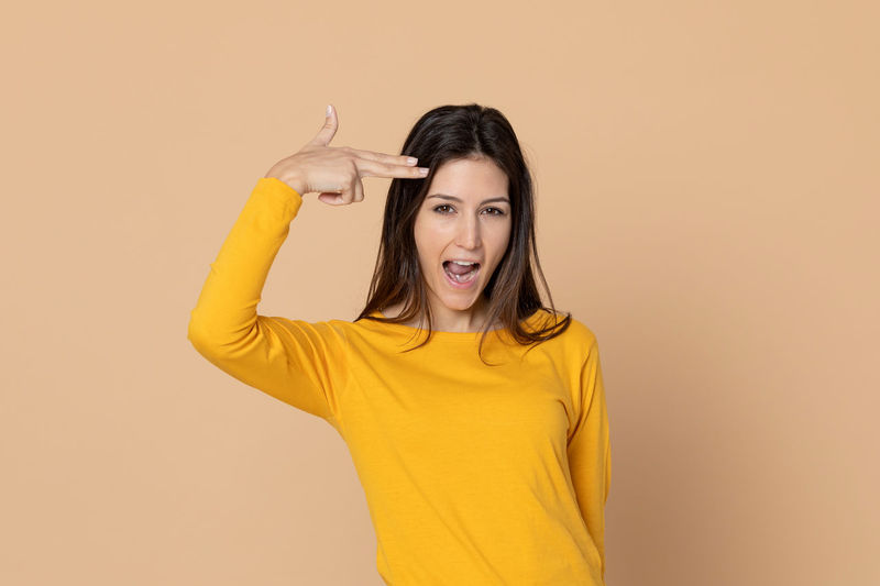 Portrait of smiling young woman standing against yellow background