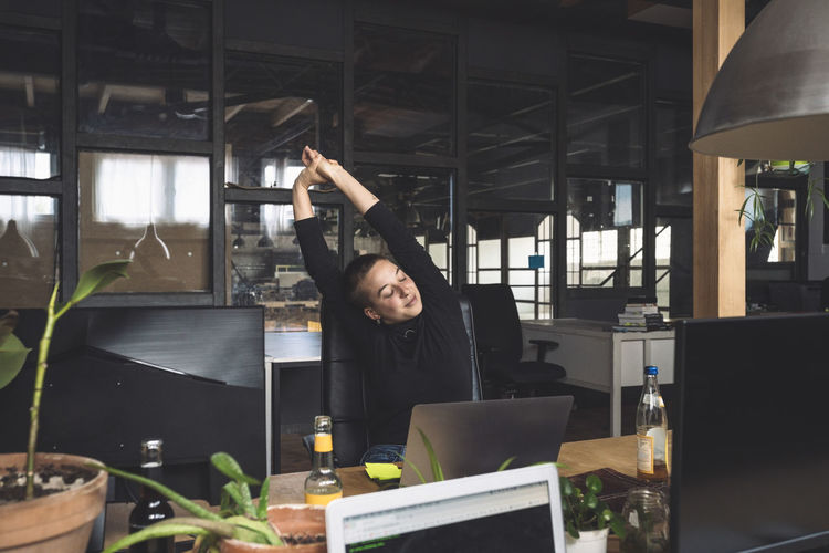 Freelancer stretching by desk at workplace