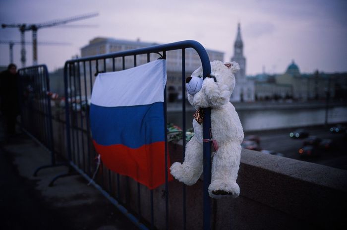 Teddy bear and russian flag on barricade against buildings in city